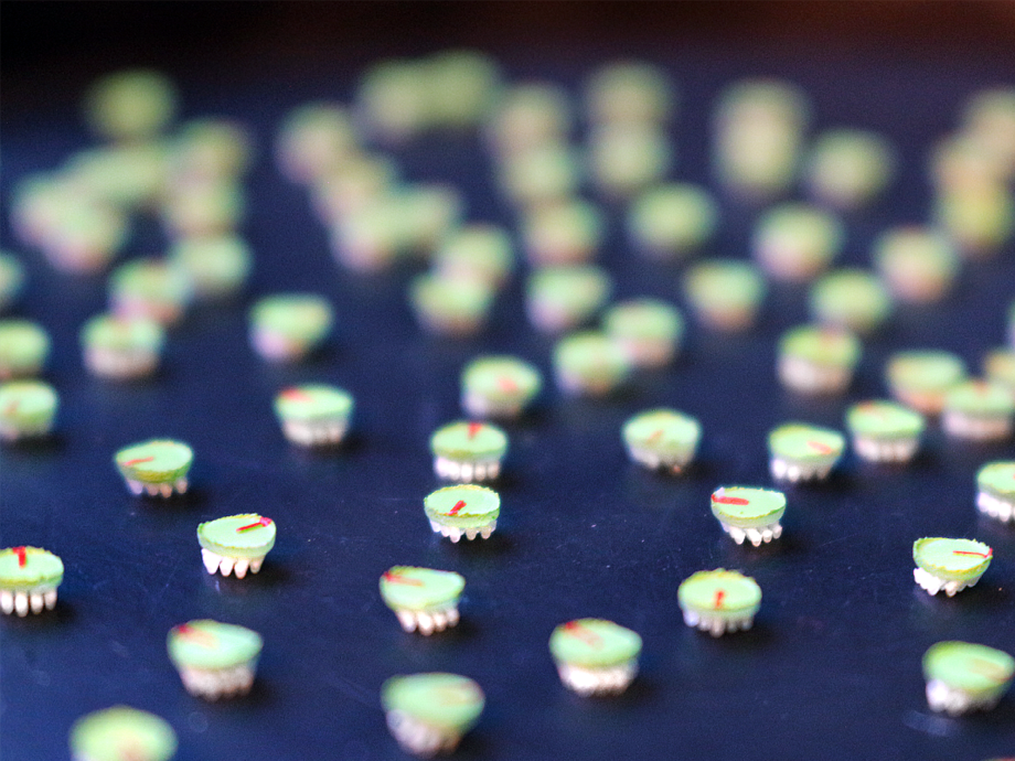 dark blue table top covered in very small light colored robots. shot in perspective where the forfront is in focus and the background is blurry